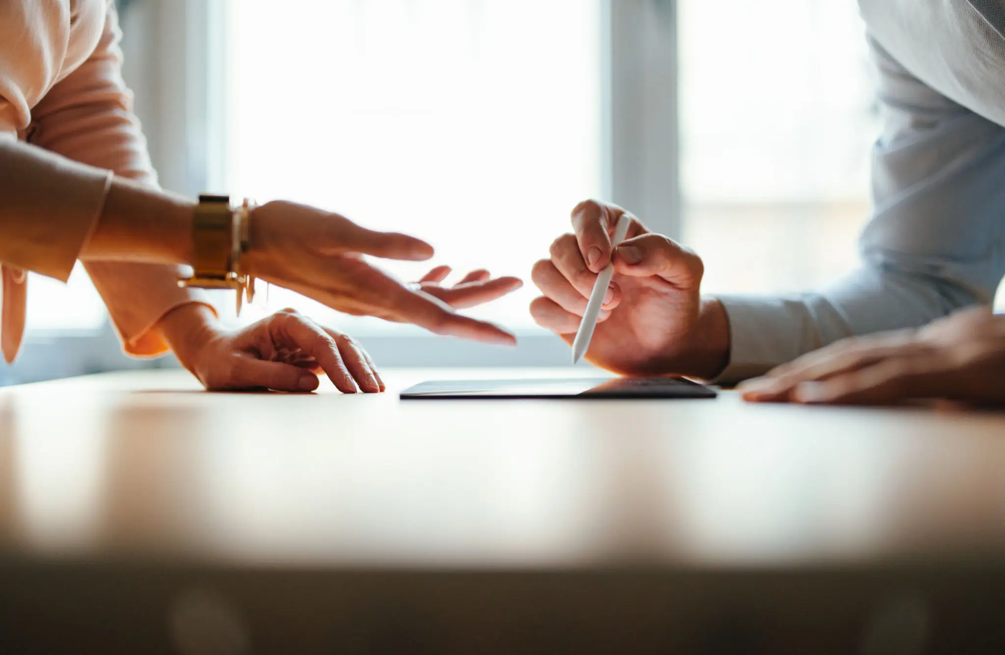 Two people using gestures while discussing over a tablet.