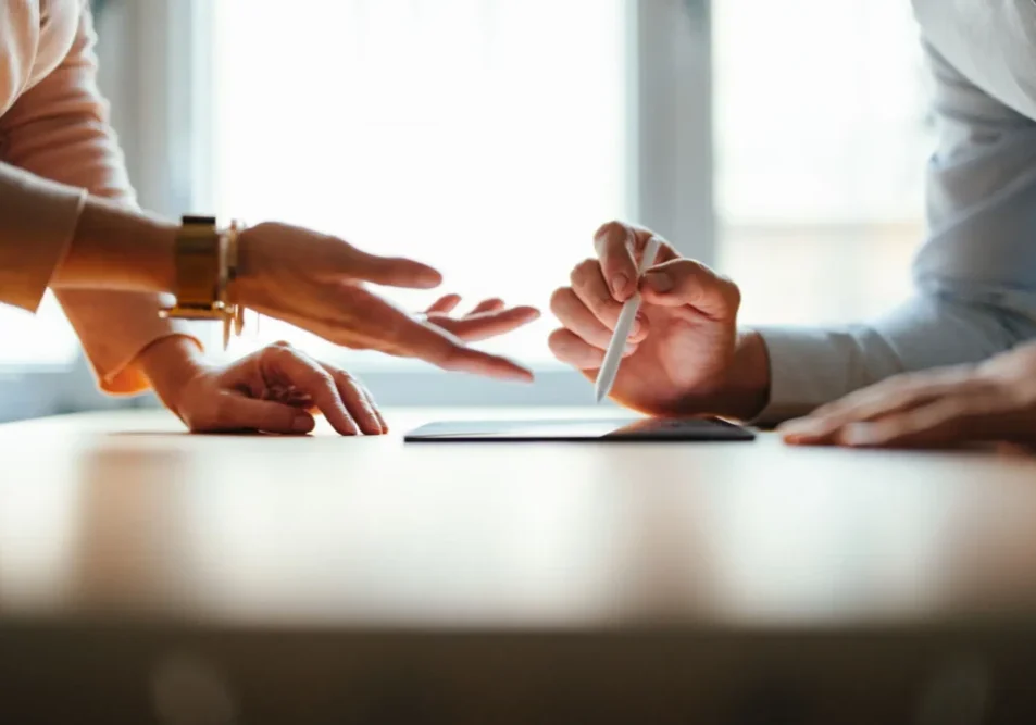 Two people using gestures while discussing over a tablet.